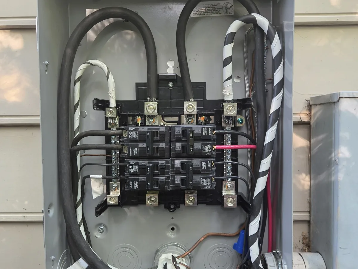 An open electrical panel with wires and breakers exposed while work is in progress, in Oakwood, Raleigh