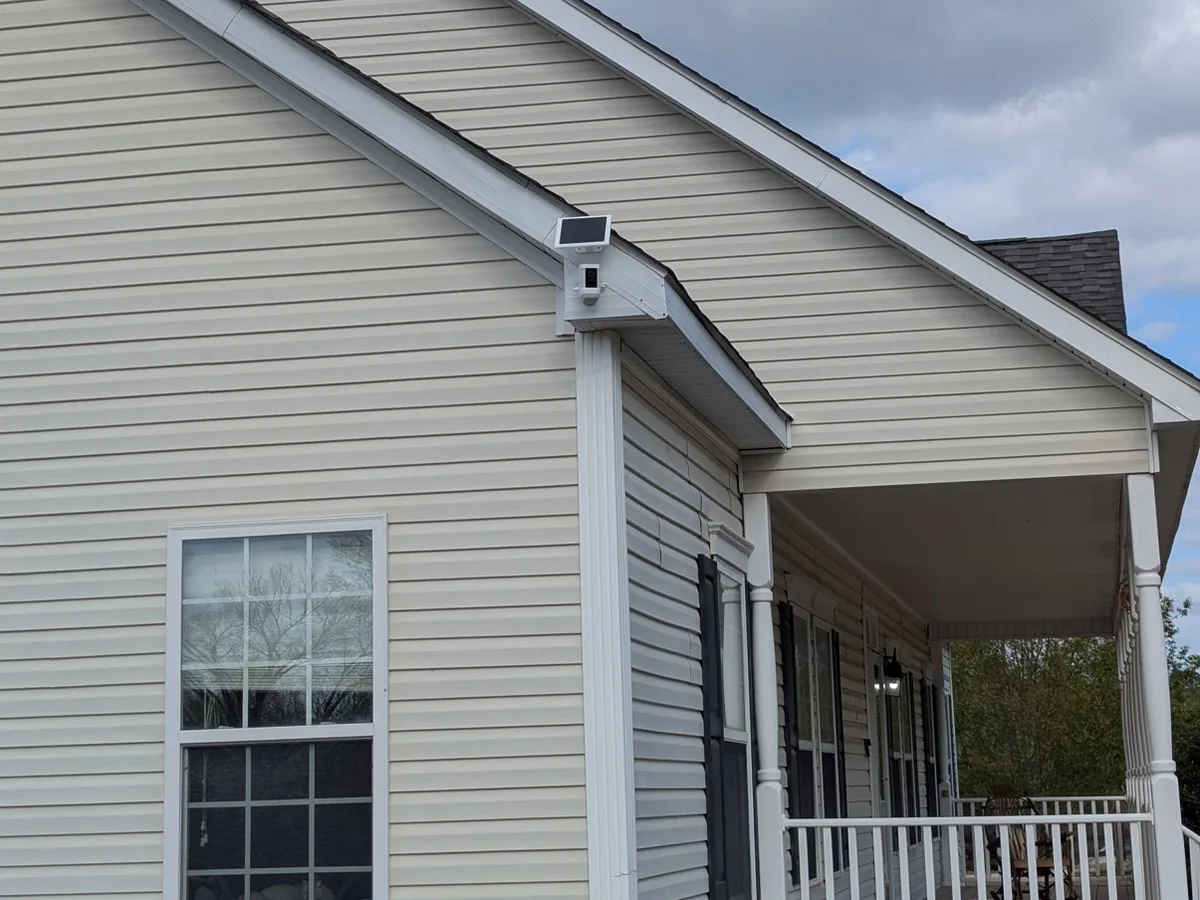 Solar-powered security camera mounted on the exterior of a house