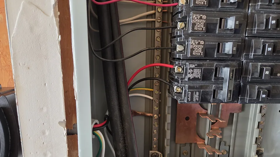 Open electrical panel with breakers and wiring being inspected
