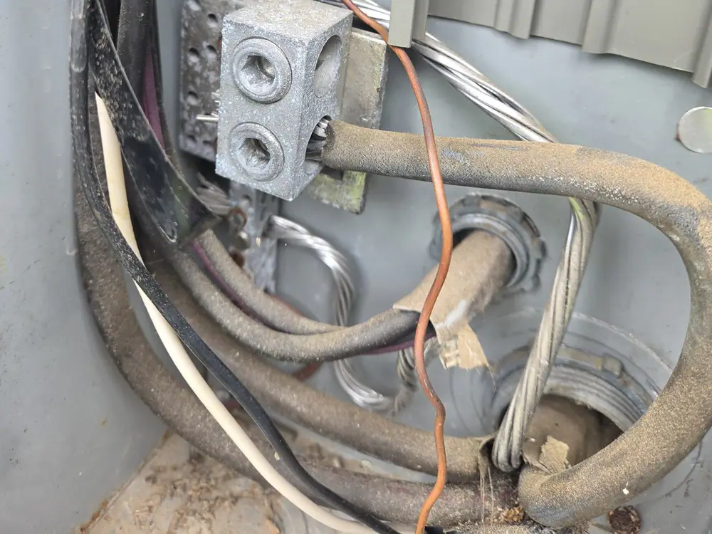 Exposed electrical wiring and metal connectors inside an outdoor panel enclosure near the meter mast in Cameron Park, Raleigh