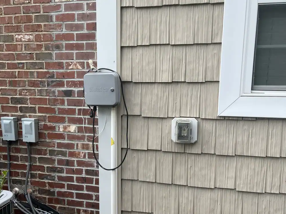 Outdoor outlets and a wall-mounted equipment box on a post beside a brick wall in Downtown Wake Forest, Wake Forest