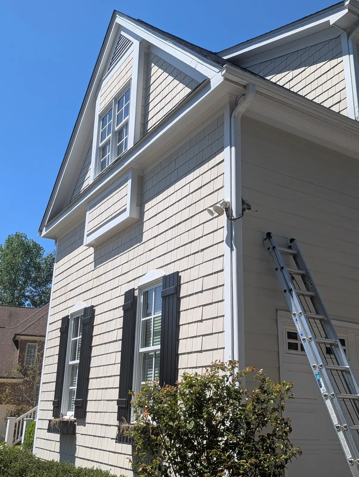 A ladder leaning against a house with a security camera mounted near the gutter, in Budleigh, Raleigh