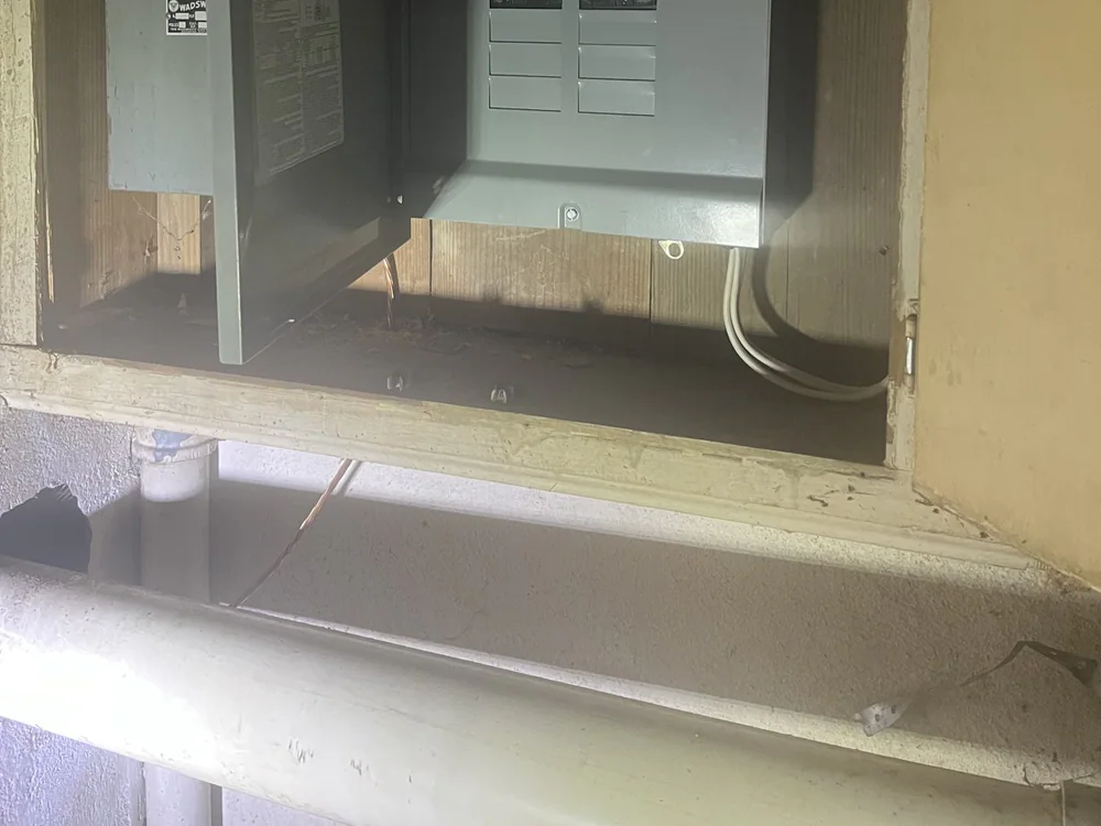 Electrical panel with its door open inside a wooden enclosure, showing internal components and wiring, in Mordecai, Raleigh