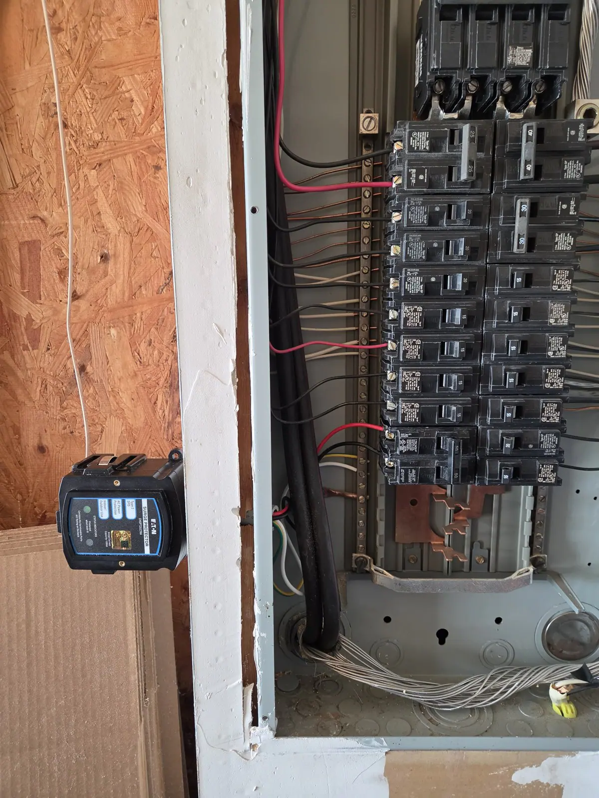 Electrical panel with a surge protector in place and wiring exposed during the installation, in Wakefield, Raleigh