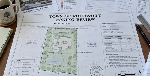 Site plan and zoning papers laid out on a desk for a town review