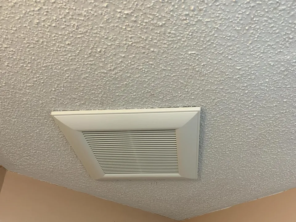 Bathroom exhaust fan with a built-in light in a textured ceiling