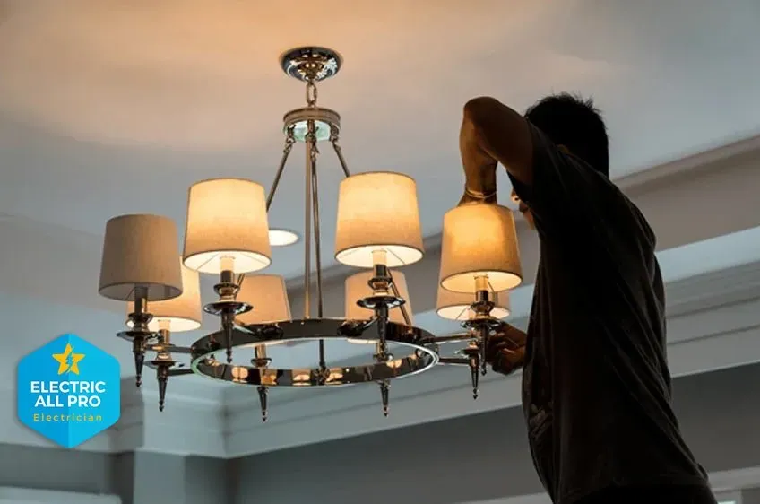 Electrician hanging a chandelier in a Raleigh dining room