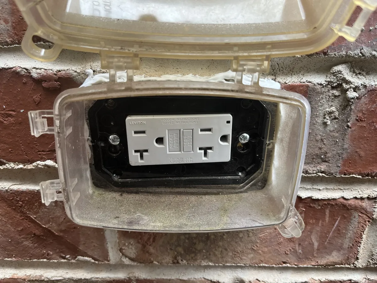 GFCI outlet in a weatherproof in-use cover on a brick wall, installed by Electric All Pro in Raleigh, NC