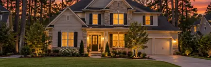 Two-story house among tall trees in a planned community at sunset