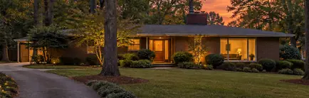 Mid-century home on a curving, tree-lined lane at sunset