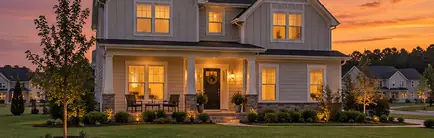New two-story home with a front porch in a growing subdivision at sunset