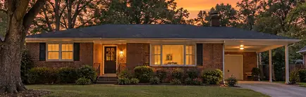 Mid-century brick ranch house with a low-pitched roof at dusk
