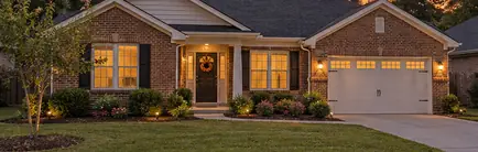 Newer single-story brick home with a small front lawn at sunset