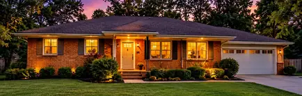 Mid-century brick ranch home with a garage at dusk