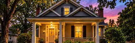 Older craftsman-style home with a lit front porch at dusk
