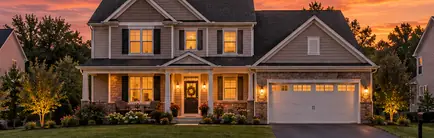 1990s two-story suburban home with a front porch and garage at dusk