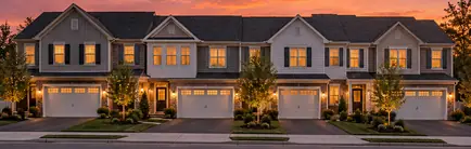 Row of two-story townhomes with garages at sunset