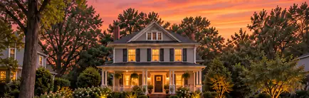 Pre-war two-story home with a deep porch at dusk