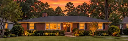 Sixties brick ranch with a low roofline at dusk
