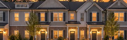 Row of newly built townhomes with small front yards at sunset
