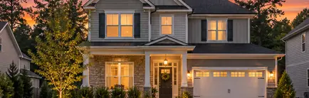 Newer two-story subdivision home with a front lawn at dusk