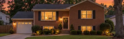 Brick split-level house from the 1980s with a single-car garage at dusk